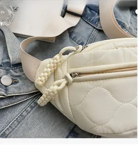 Detail der beigen gesteppten Gürteltasche mit glattem Reißverschluss und verstellbarem Gurt