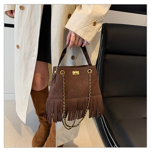 Gros plan du sac seau en daim marron avec texture matelassée et détails de franges