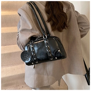 Detail of glossy black tote bag featuring silver eyelets and a leather brand tag