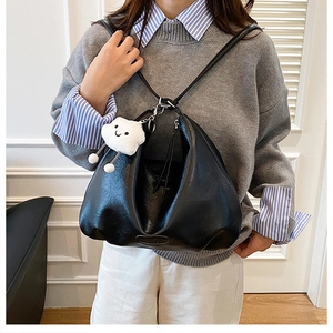 Detail of black soft PU leather backpack with vintage folds and cute cloud pendant
