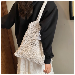 Detail view of a woven tote bag featuring white lace trim and elegant pearl charms