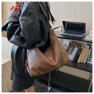 Nahaufnahme der großen braunen Leder-Hobo-Tasche mit Goldlogo und verstellbarem Gurt