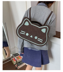 Detailed view of the cat-shaped brown backpack with mint green embroidery on model
