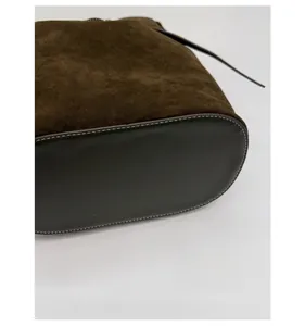 Détail du fond renforcé en daim du sac seau avec coutures contrastées en cuir lisse marron
