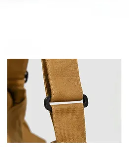 Détail du sac bandoulière vintage en toile montrant la texture kaki et la boucle en plastique