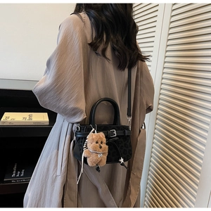 Detailed view of a leopard print handbag with a cute teddy bear charm and silver buckle strap