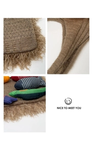 Detail of dark brown knit cat mat with plush tassels and colorful fabric fish charms
