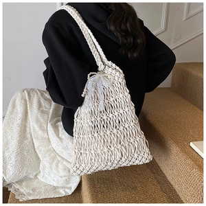 Detailed close-up of woven straw tote bag with pearl bow and lace edge trim