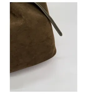 Détail du sac seau en daim olive montrant les coutures contrastées et la texture