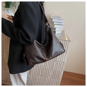 Nahaufnahme der dunkelbraunen Hobo-Tasche mit feiner Ledertextur und goldenem Emblem