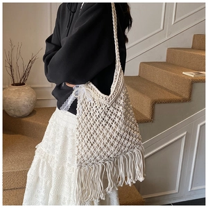 Detail of handmade macramé beach tote with long fringes and delicate white lace ribbon