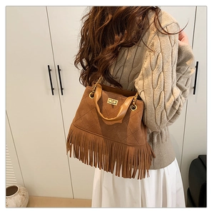 Gros plan détaillé d'un sac seau en daim marron avec de longues franges et chaîne dorée