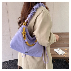 Detail of purple fabric crossbody bag with yellow rope knot and ruffled shoulder strap