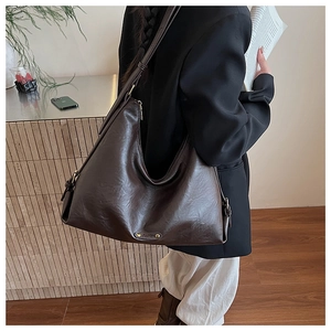 Detail der dunkelbraunen Leder-Hobo-Tasche mit dekorativer Fashion-Metall-Logoplatte