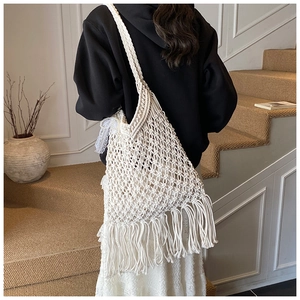 Detailed view of the white handmade woven mesh tote bag with long bohemian tassels