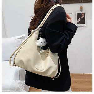 Detail of cream hobo bag with leather texture and cute white cloud charm decoration