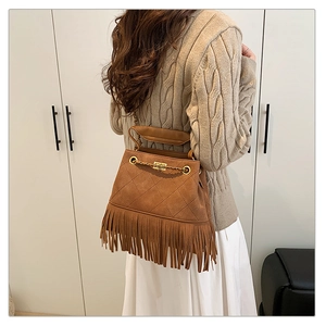Détail du sac seau marron en daim à franges avec surpiqûres matelassées et chaîne dorée
