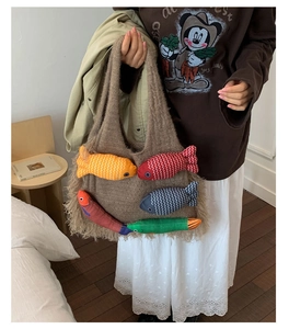 Close-up of knit tote bag with colorful 3D fish decorations and beige fringe trim detail