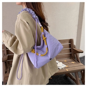 Close-up of purple nylon crossbody bag featuring ruffled strap and yellow contrast cord