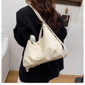 Detail of creamy white PU leather tote with cloud pleats and cute rabbit pendant charm