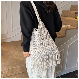 Close-up of bohemian woven tote bag showing fringe detail and open mesh texture