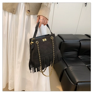 Détail de sac seau noir matelassé avec fermoir doré et longues franges bohèmes