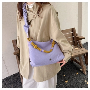 Outdoor lifestyle view of lavender nylon crossbody bag with yellow knot handle detail