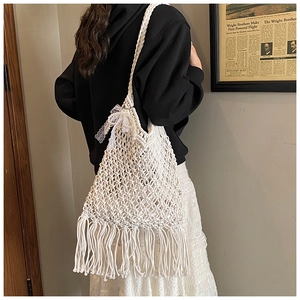 Detail of white hand-woven mesh tote with long fringe tassels and lace bow decoration
