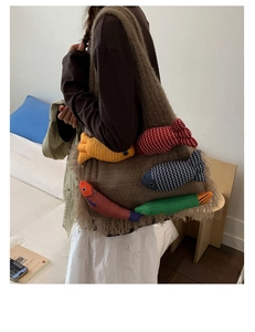 Detailed shot of large knit tote bag with 3D stuffed fish dolls and fringe accents