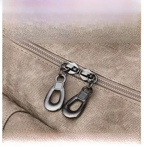 Close-up of dual gunmetal zippers on vintage khaki canvas backpack showing stitch detail
