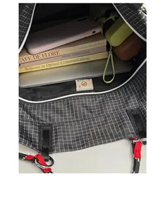 Vista dall'alto di capiente borsa shopper a quadretti con laptop, libri e oggetti vari