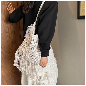 Detail of white handmade woven crochet bag with long tassels and delicate lace accents