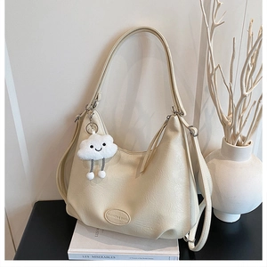 Detail of cream PU leather hobo bag with fashion logo and plush cloud charm