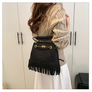 Vue détaillée du sac bandoulière noir avec des franges et une chaîne dorée