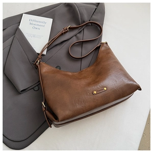Detail einer braunen Leder-Umhängetasche in Halbmondform mit Vintage-Beschlägen und Riemen