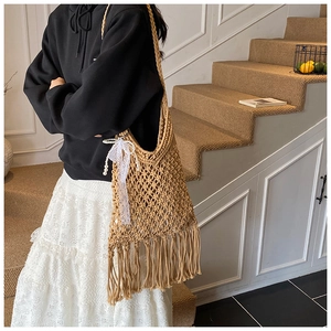 Detail of hand-woven mesh tote with long fringe tassels and lace bow with pearl charm