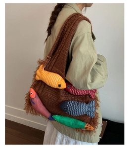 Detailed knit texture of brown tote bag featuring colorful plush fish charms and fringe