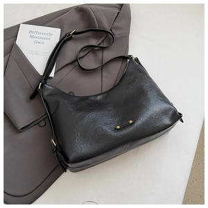 Details einer schwarzen Hobo-Tasche in Halbmondform mit goldenem Fashion-Emblem