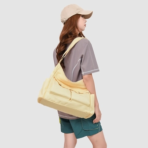 Vue détaillée du grand sac bandoulière en toile jaune pâle avec design multi-poches sur modèle