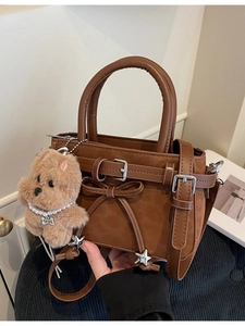Brown leather handbag with leopard detail, bow pendant, and plush dog charm accessory