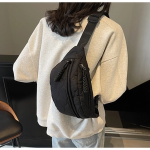 Détail d'un sac bandoulière noir matelassé avec sangle réglable porté sur le corps
