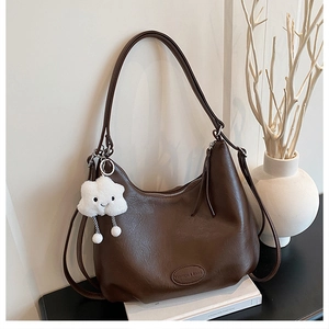 Detail of dark brown leather tote bag with cloud charm and embossed logo on the bottom