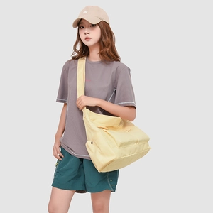 Vue détaillée du grand sac bandoulière en toile jaune porté par un mannequin