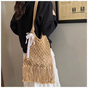 Detail of handmade woven tote bag with fringe tassels and a lace bow charm accent