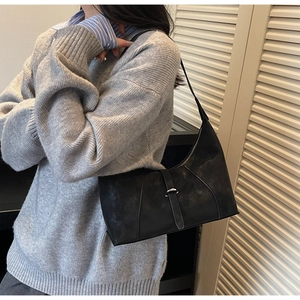 Close-up of black retro hobo bag with matte finish and vertical decorative strap detail