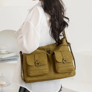 Detail of olive green canvas crossbody bag with dual utility front pockets and metal rings