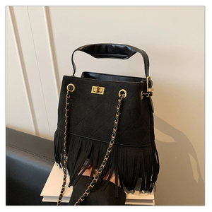 Détail du sac seau à franges en daim noir avec motifs matelassés et fermoir doré