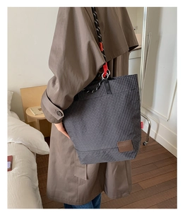 Dettaglio della borsa tote a quadri con tracolla intrecciata a tre colori e logo in pelle