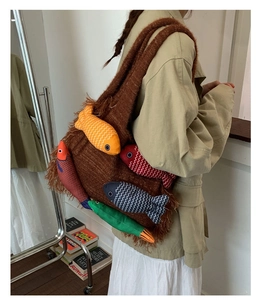 Detail of a brown knit tote bag with five colorful plush fish dolls and side fringes