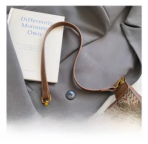 Detail of brown leather bag featuring ethnic woven strap and vintage gold metal buckles